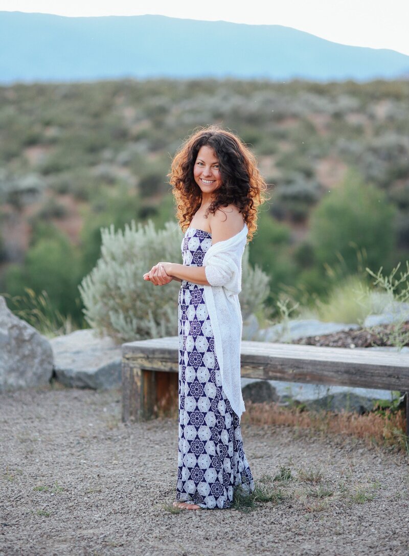 a photographer standing smiling in front of a bridge