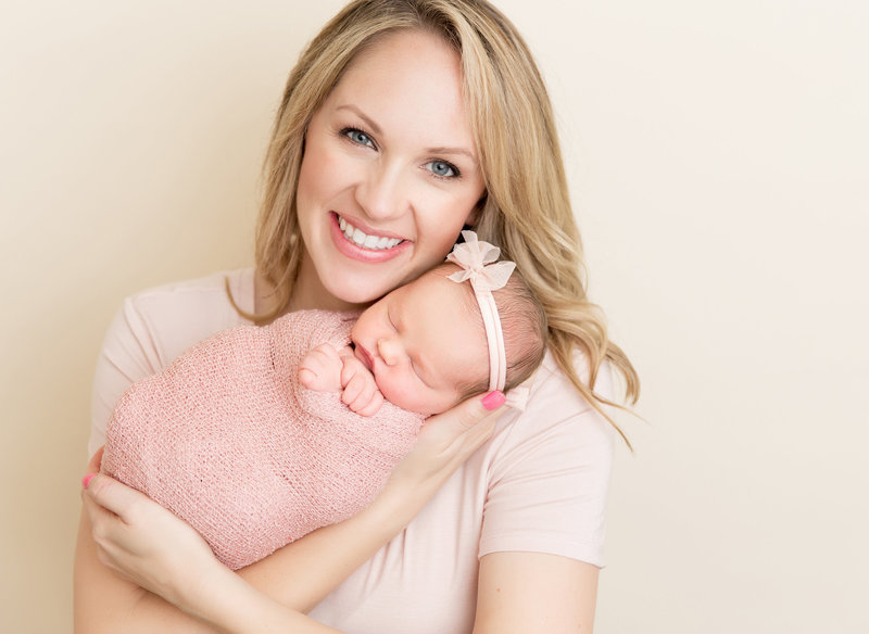 blonde mom holing baby girl in pink