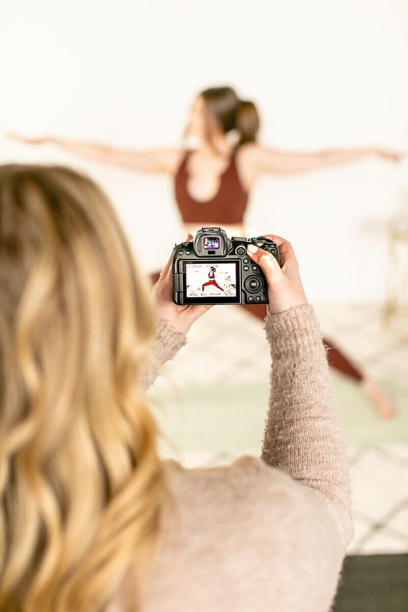 Photographer taking photo of brunette woman doing yoga pose