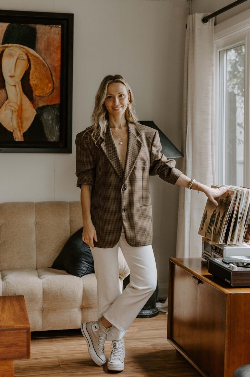 Woman standing in a studio wearing a blazer and white pants sigh-quality modular jewelry, slow fashion, and sustainable living services in Hamilton, Ontario