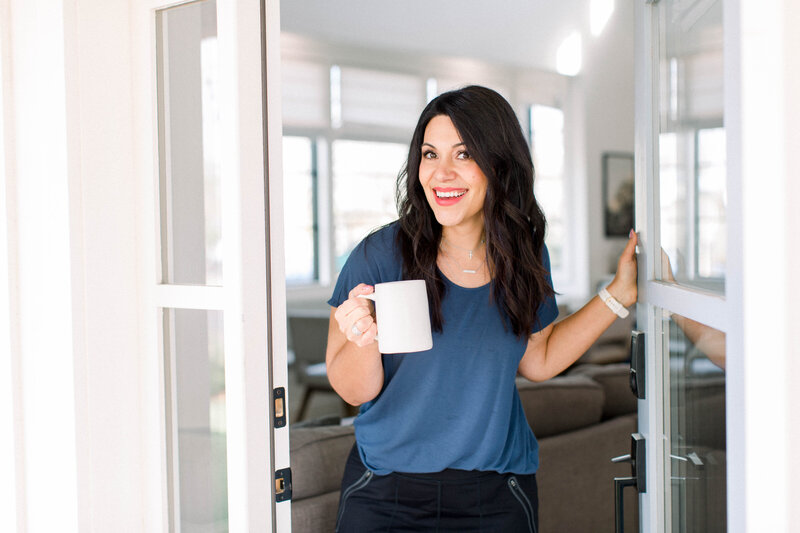 Stefanie Gass smiling with coffee cup walking through door
