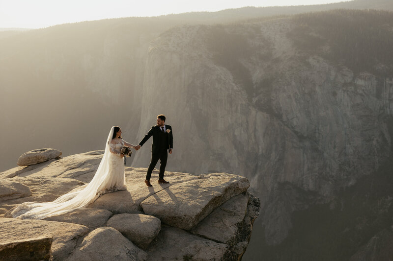 Bride and groom standing at taft point yosemite on their elopement day