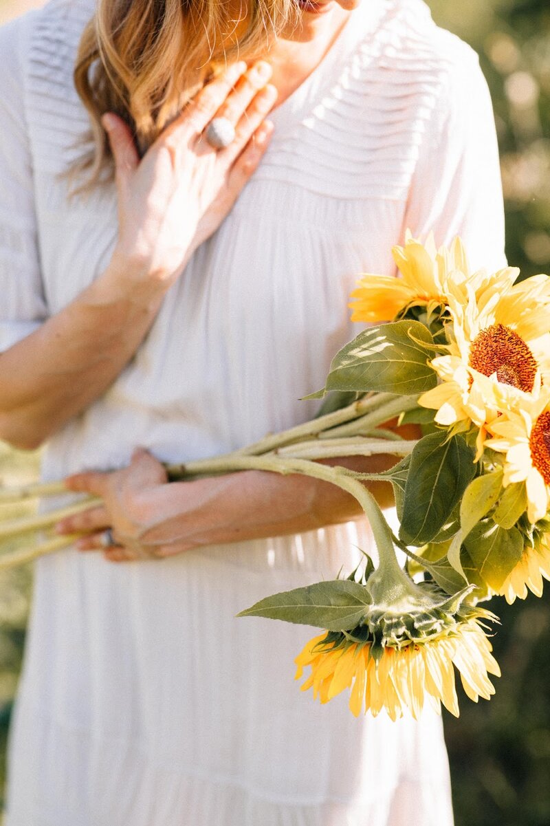 holding sunflowers in a field