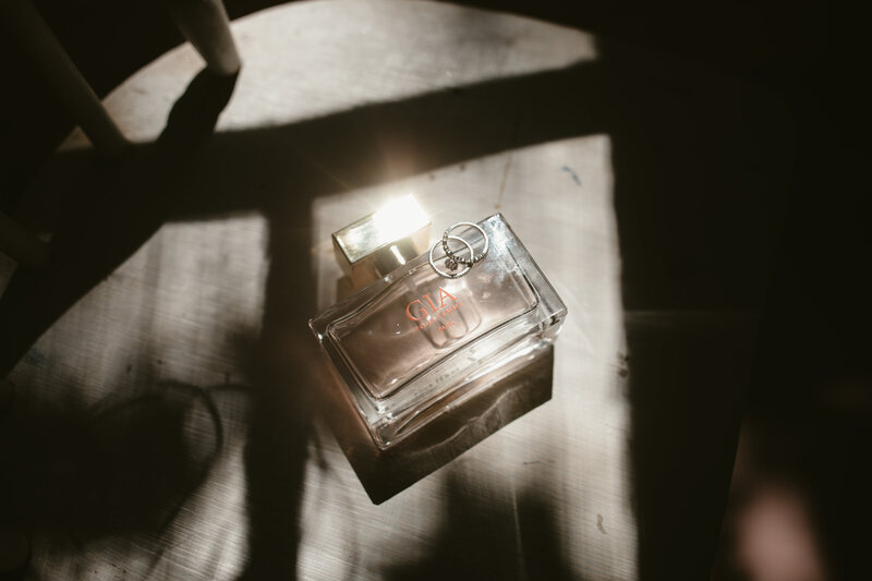 Wedding invitation and jewelry captured in artistic light by Jessica from Rainstorm Photo & Video, showcasing the fine details of the wedding day.
