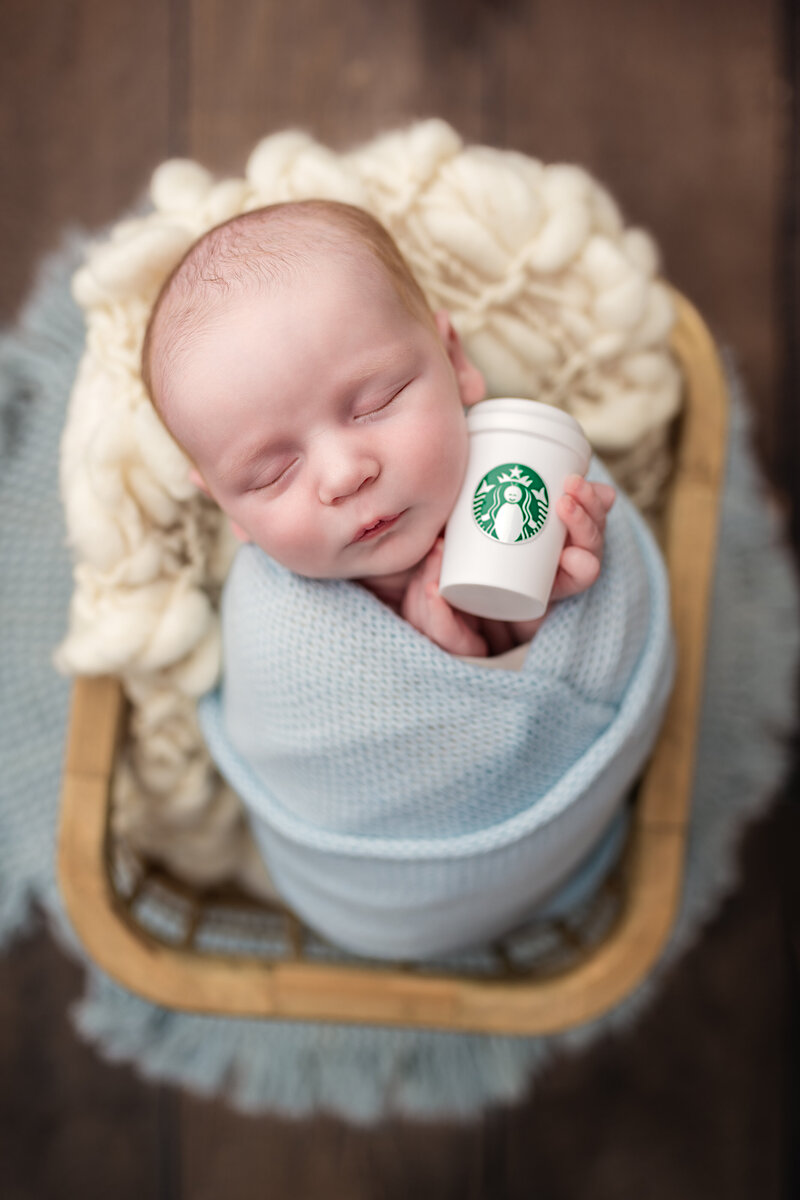Baby boy wrapped in blue with a mini Starbucks cup—adorable newborn session with personality in Paris, Ontario.