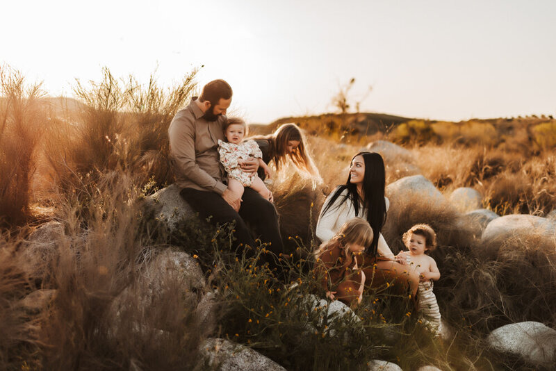 Family sitting on boulders at sunset in Bakersfield, CA.