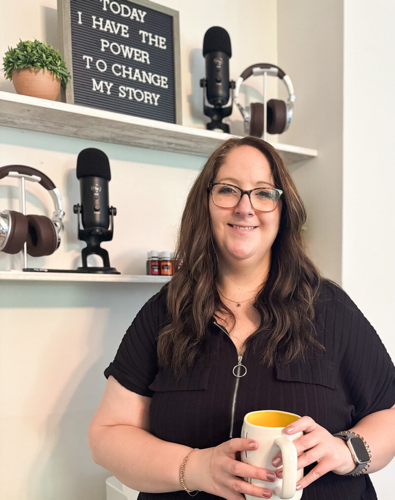 Marketing strategist smiling with coffee mug in hand in front of podcast setup