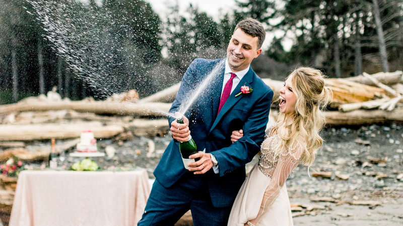 bride and groom popping champagne on the beach wedding site