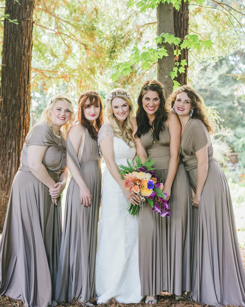 Bridesmaids surround Bride in the middle as they all smile at the camera