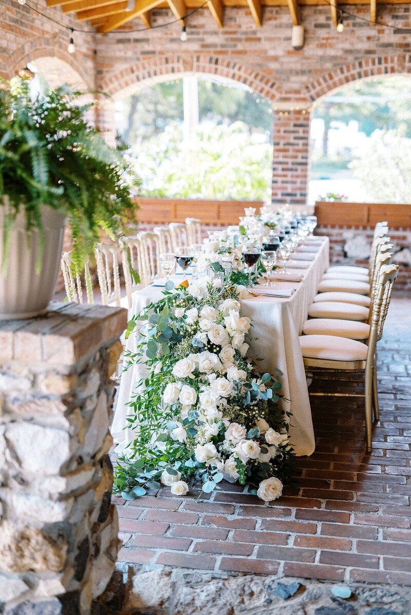 a white floral cascade centerpiece, black goblets, and a light tablecloth, set in the century room at grbic events in st. louis