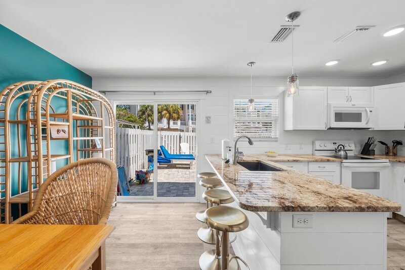 Bright kitchen with granite counters and view of private patio with loungers at Tropical House, perfect for PCB vacation stays near the beach.