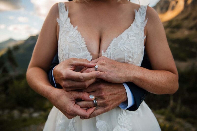 A bride and groom hold one another and admire their wedding rings on their wedding day in Montana.