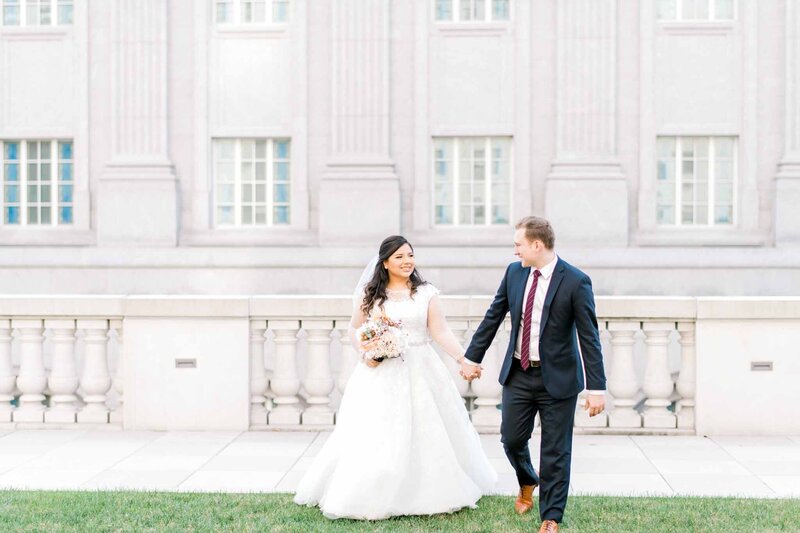 Bride and groom walking in front of building