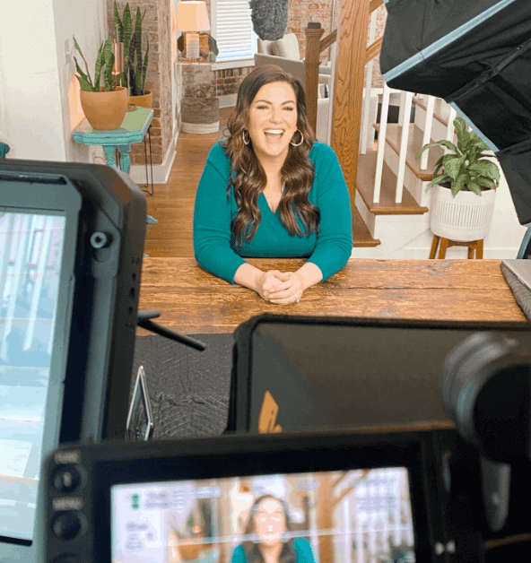 Amy Porterfield sitting at a wooden desk at home  and filming a video