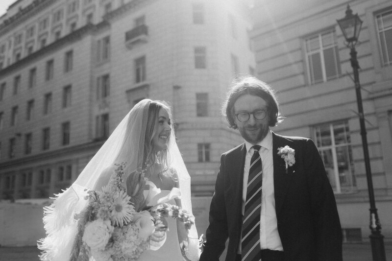 Editorial (oh me oh my liverpool) (city) black and white photo of a newlywed couple smiling after the ceremony, with classic architecture behind them.