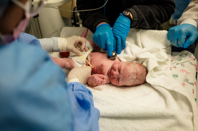 Newborn baby moments after delivery in hospital room — powerful DFW birth photography by Poppy + Blue Photography