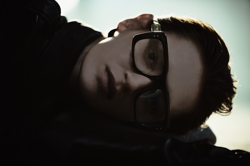 Shot of a woman laying on the ground wearing wide framed luxury glasses.