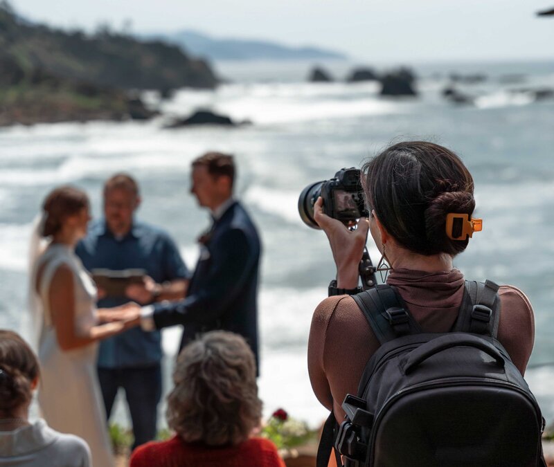 a photographer holds a camera taking a picture of a wedding ceremony