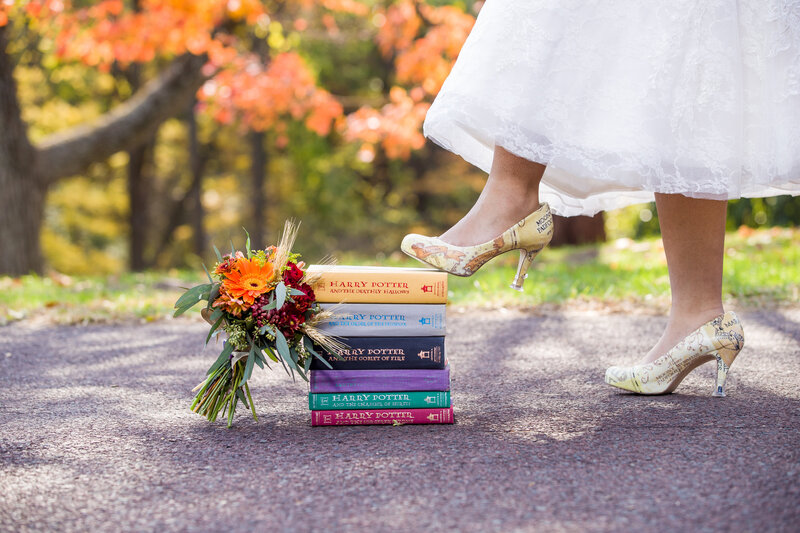 Bride standing on a stack of Harry Potter books, showcasing her love for literature in a unique wedding detail shot.