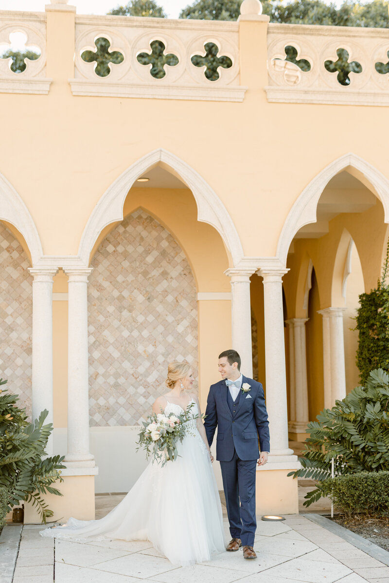 Bride and groom smile brightly while holding multi-colored bouquet