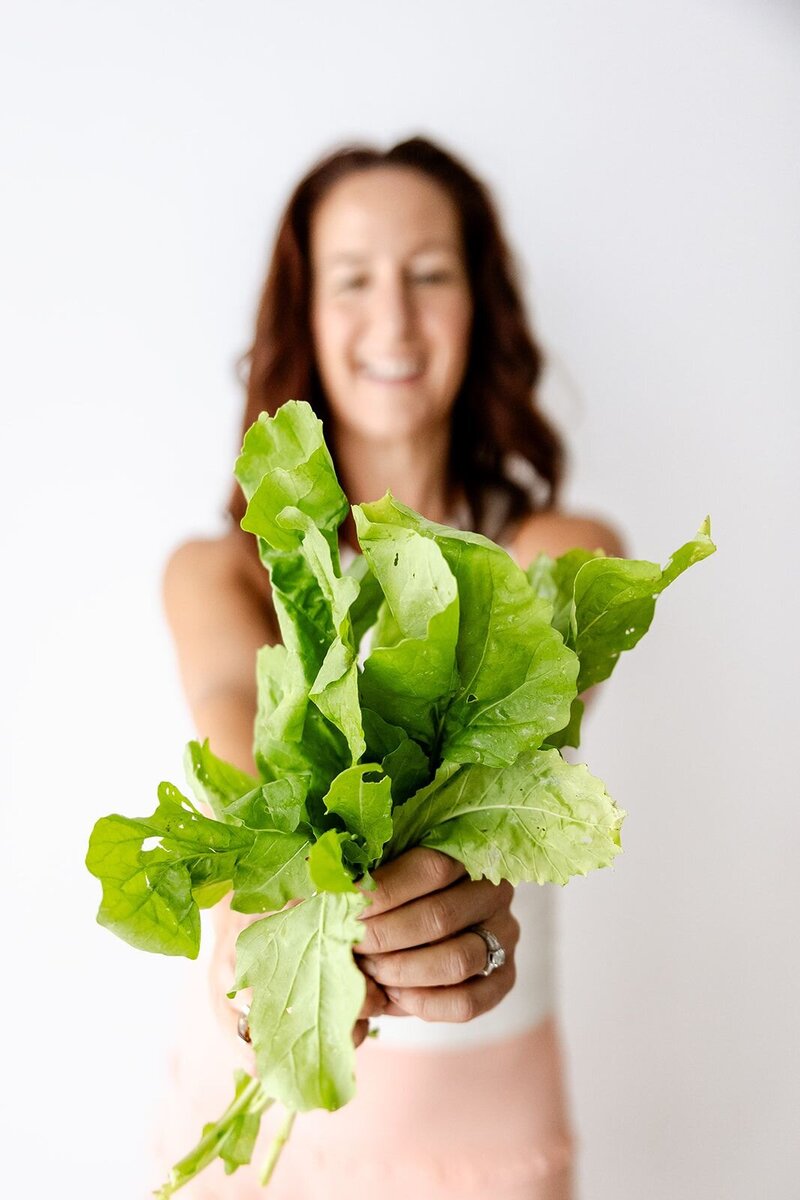 Sara Warden, Holistic Wellness Coach holding a bunch of lettue