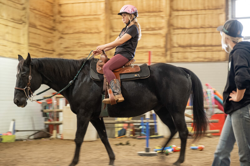 A facilitator at Spirit's Respite Ranch guiding a horse used for equine therapy, therapeutic riding, and horse-powered reading