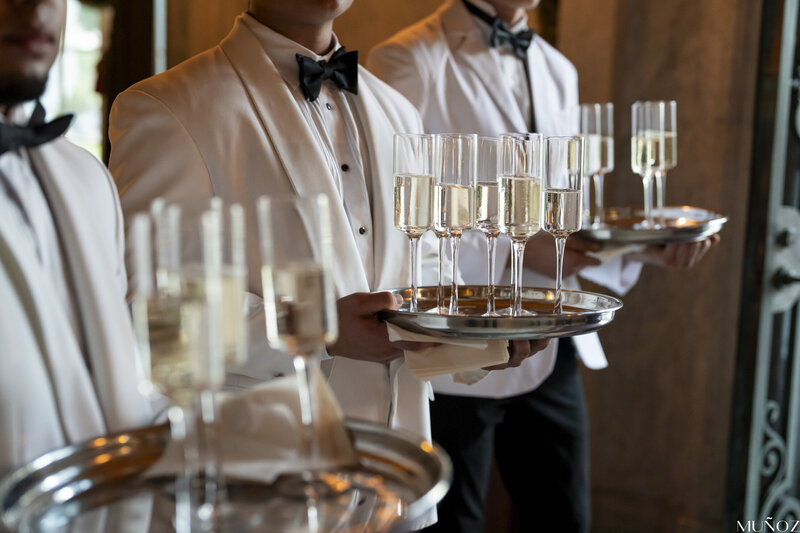 A waiter in formal attire holds a tray of champagne flutes, embodying the sophistication and attention to detail at events by Socially Significant Events