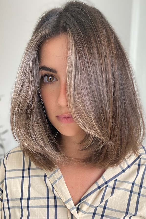 Shoulder-length layered haircut with subtle balayage, featuring smooth styling and a glossy finish.
