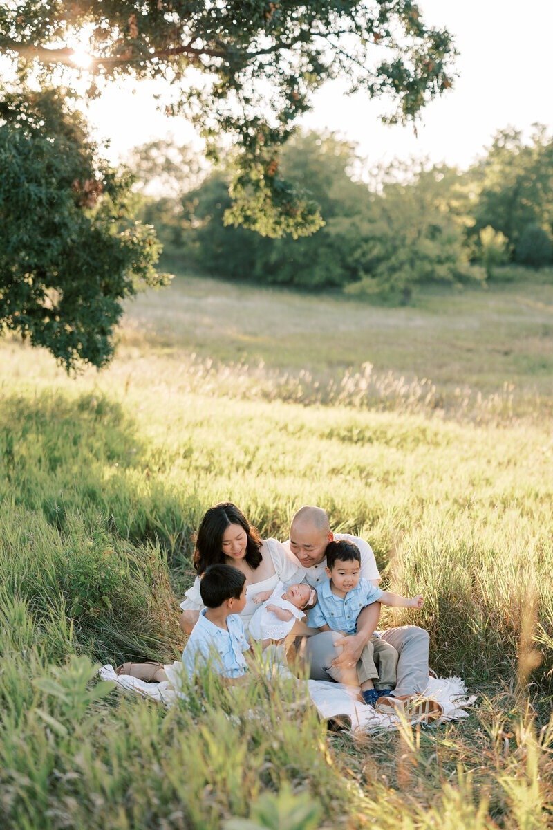 A family sitting on a blanket for a cozy outdoor portrait, captured by Emily Barbara, a family photographer in Milwaukee.