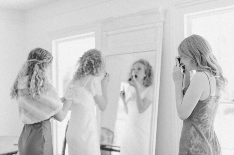 Bride’s sister Peyton Curry, a wedding photographer, taking a candid film photo of the bride and her sisters getting ready before the backyard ceremony in Richmond, Virginia.