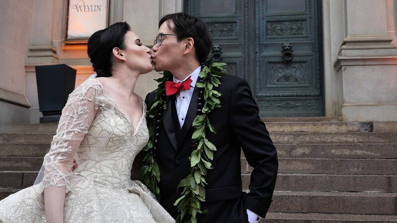 A newlywed couple kissing at the bottom of an outdoor staircase 