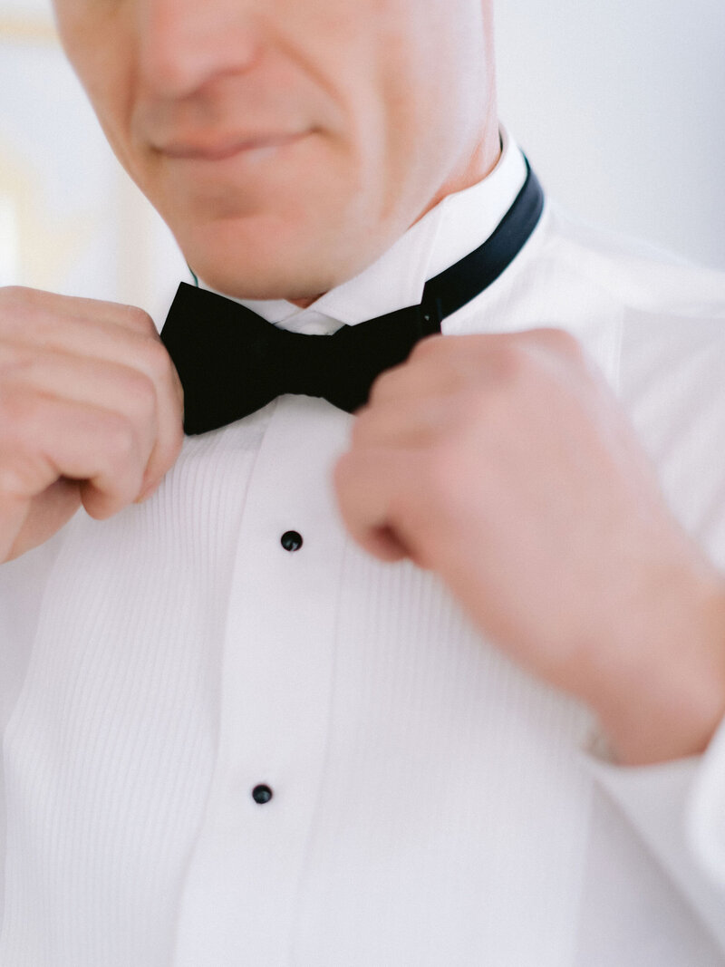 groom touching black bow tie