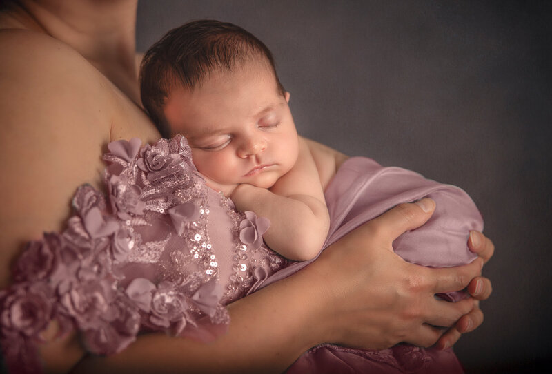 "Newborn baby girl sleeping peacefully in her mother's arms during a close-up portrait session in Ottawa"