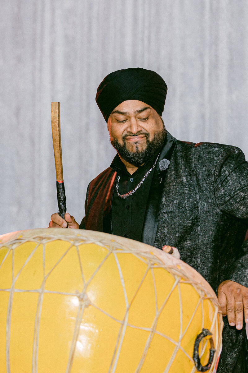 indian musician beating a yellow drum