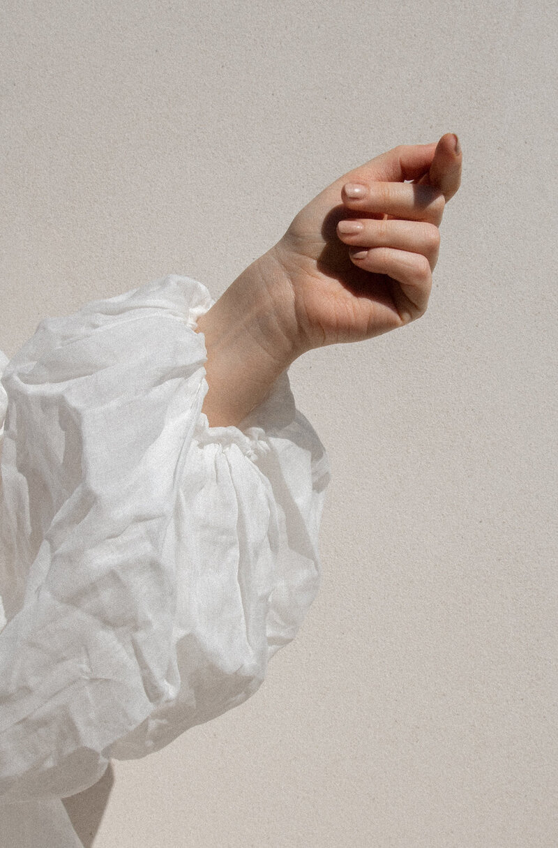 White linen shirt layered atop soft natural textures — minimalist capsule wardrobe inspiration