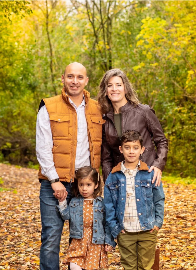 Family of four smile at the camera in fall