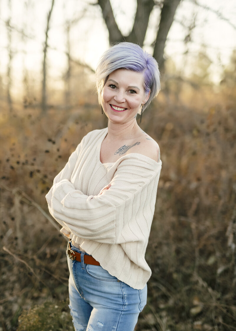 Brieanna Lebo smiling outdoors in a cream sweater and jeans during a fall portrait session.