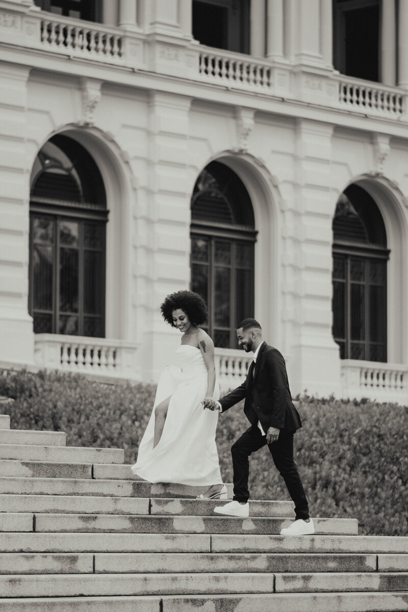 A newlywed couple poses on the steps of their venue