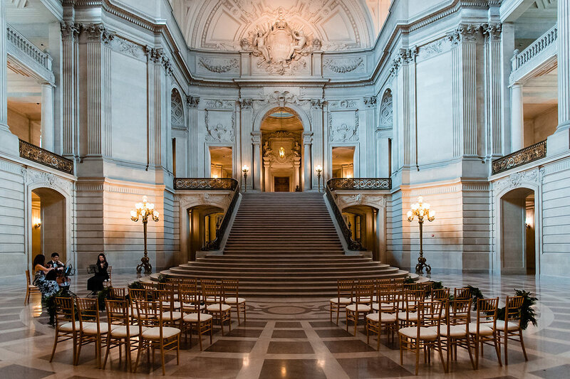 Wedding ceremony setup on San Francisco City Hall's grand marble staircase with crystal chandelier - wedding photographer