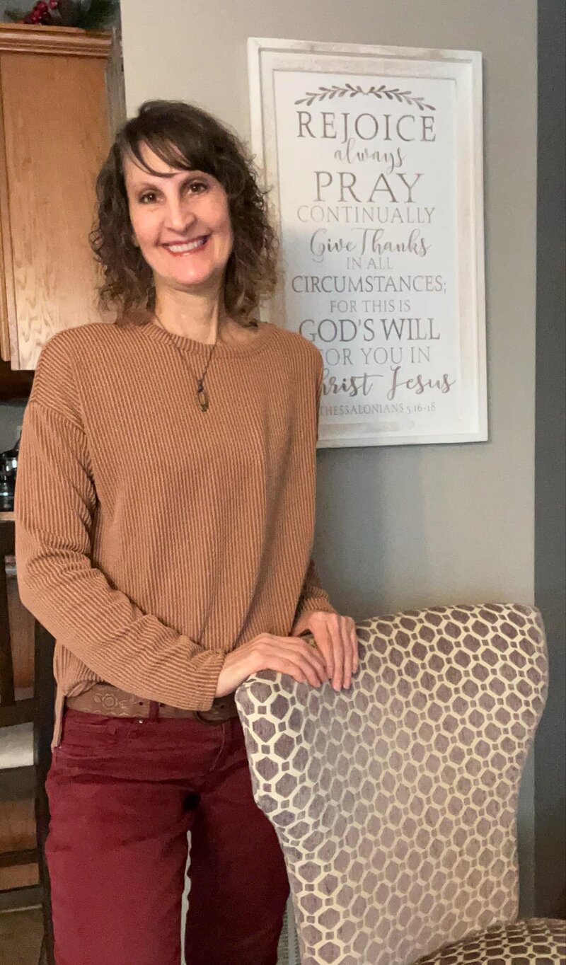 Penny smiling in her kitchen next to a chair