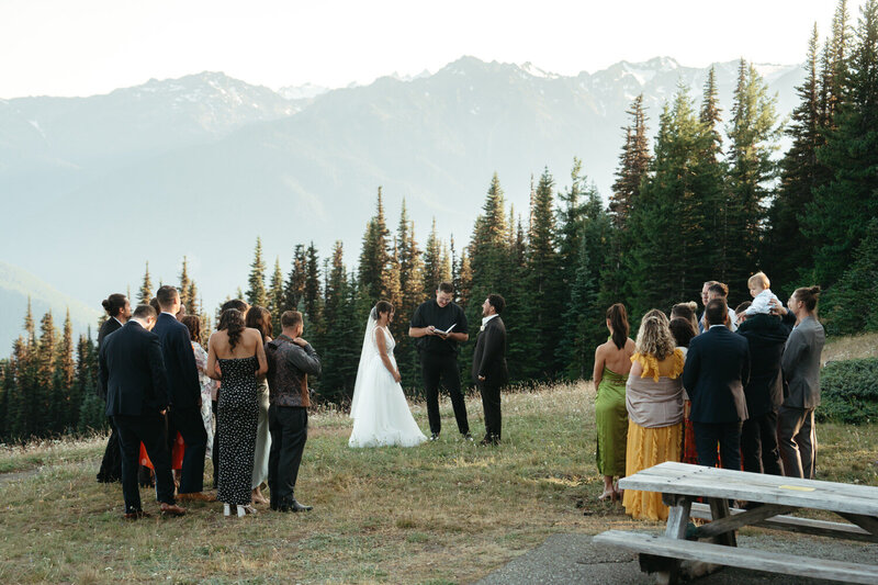 Elopement Ideas with Family | Elopement ceremony with 15 family members, surrounded by evergreen trees with mountains in the background