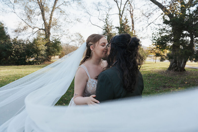 Woman's veil blows in the wind as she kisses her new wife