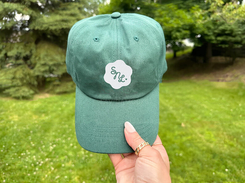 A person holds a green hat adorned with a white flower, showcasing a stylish accessory for spring or summer.