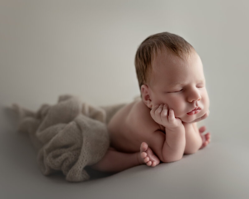 A peaceful side view of the classic froggy pose—newborn boy in soft neutrals, captured in Paris, Ontario.

