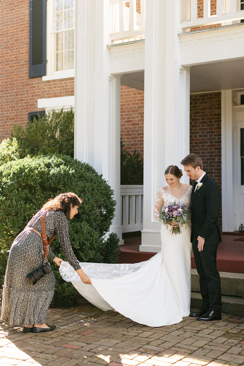 Victoria Barclay, photographer at Through Victoria's Lens, adjusting a bride's veil at a Nashville wedding