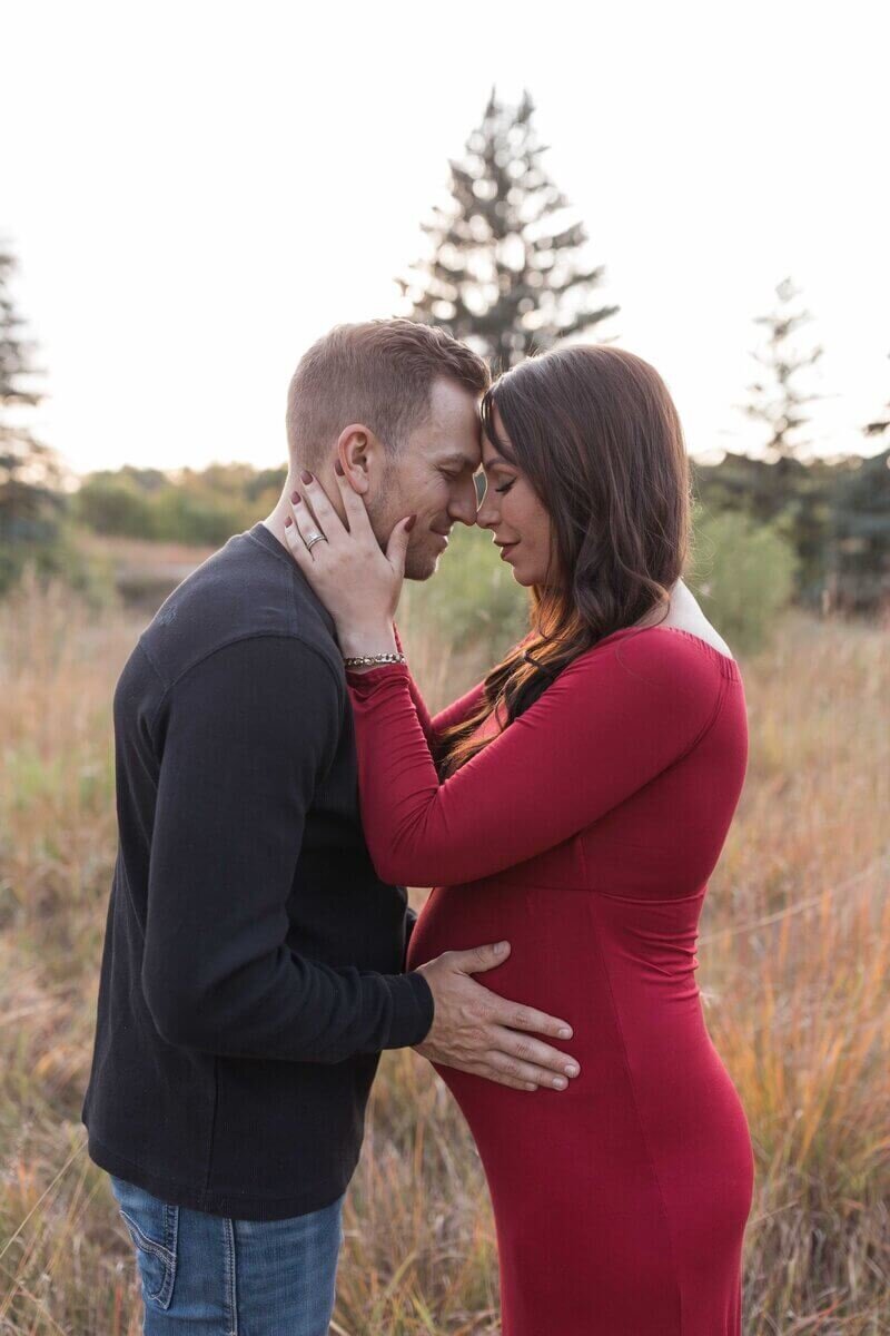 pregnant mom and dad embracing eachother at heritage hills park fargo, nd