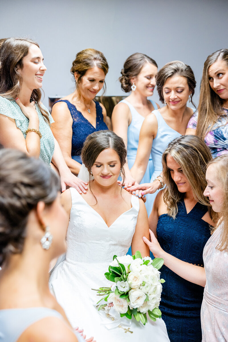 A group of bridesmaids praying over the bride before her ceremony