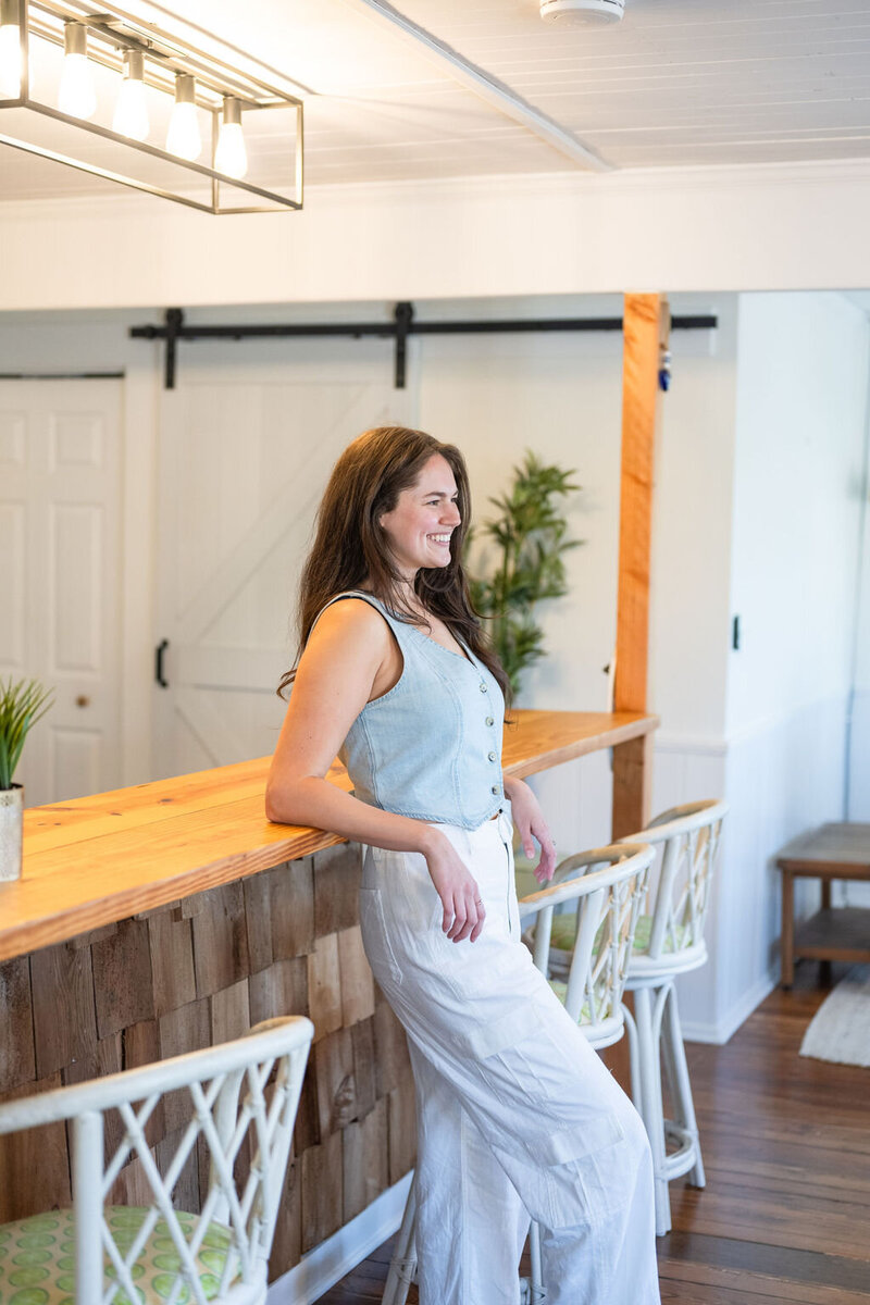 Annie leans back with her elbows up on a wooden bar