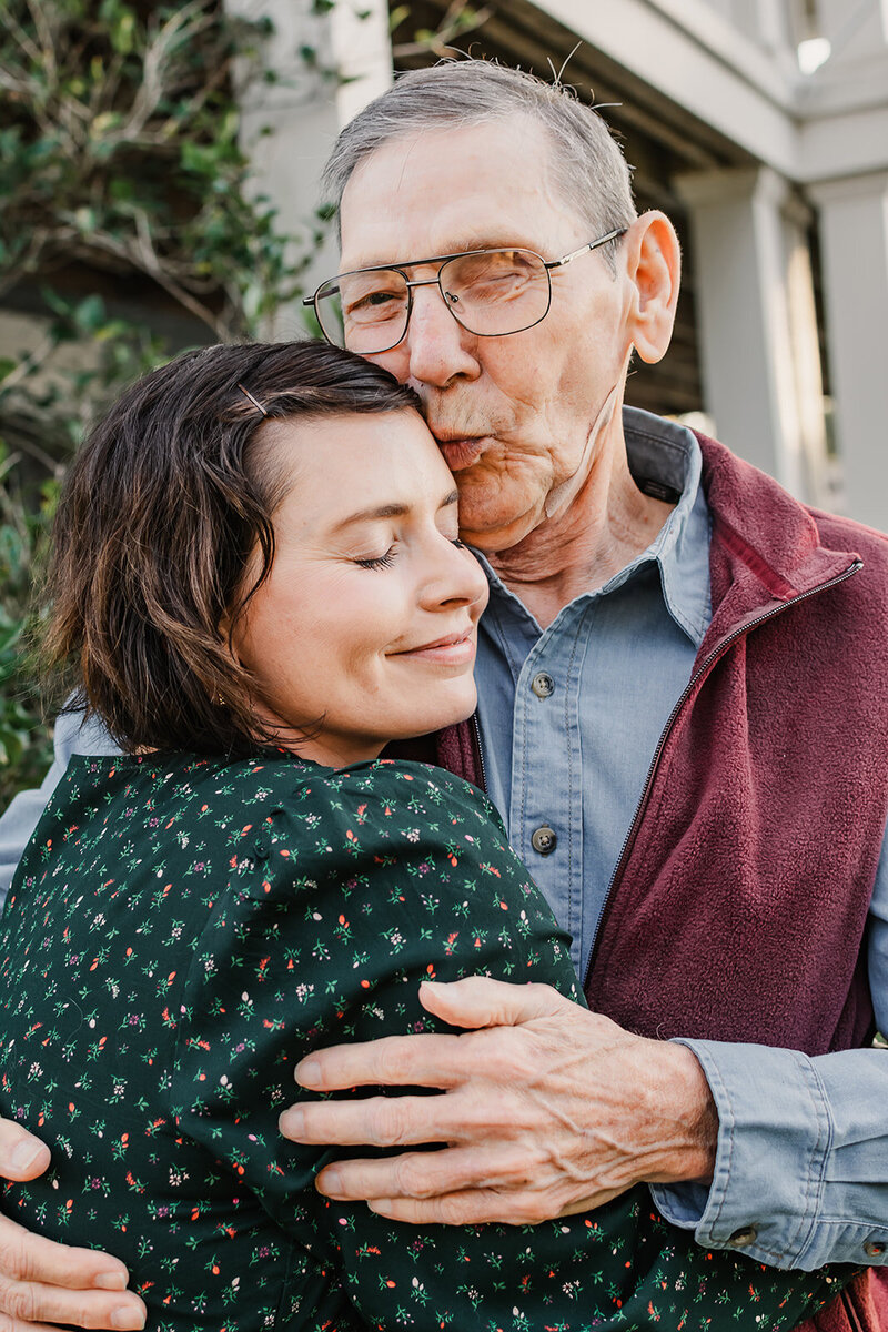 Elder father embracing his daughter with a forehead kiss. 