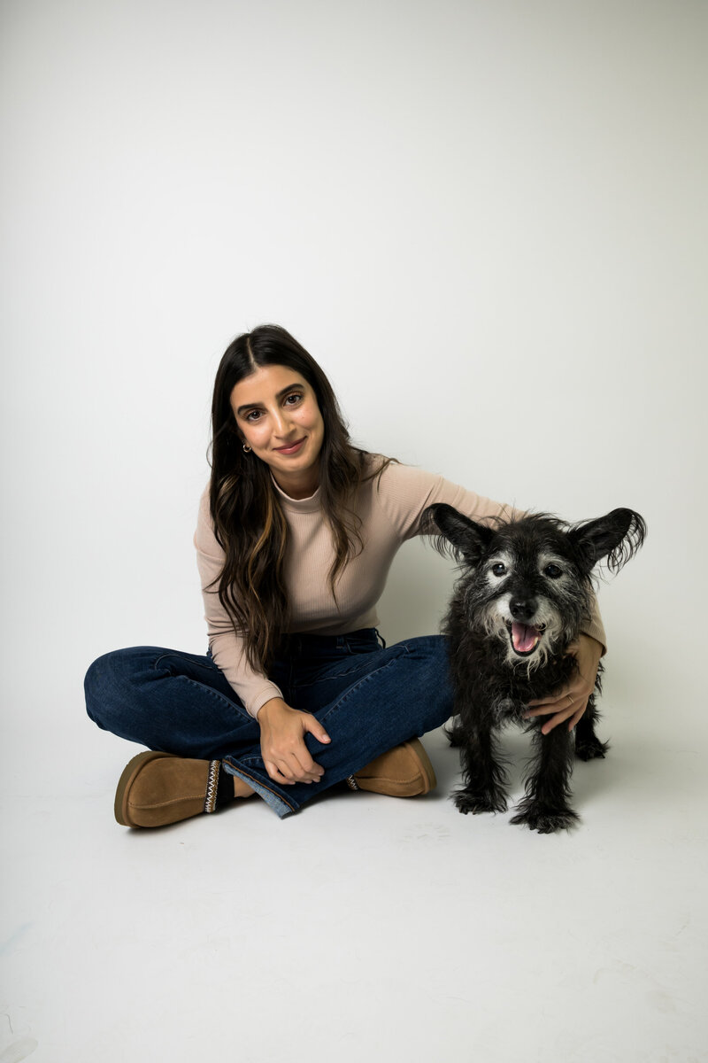 Woman and elderly dog pose for portraits in modern photo studio